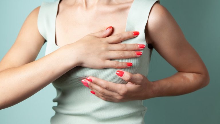 young woman wearing white top and jeans with a heart on blue isolated background